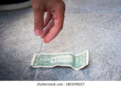 Male Hand Picking Up One Dollar Bill From The Ground.