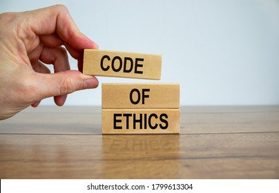 Male hand placing a blocks with word 'code' on top of a blocks tower. Text 'code of ethics'. Beautiful white background. Copy space. - Shutterstock ID 1799613304