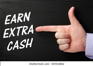 Male Hand Pointing A Finger At The Phrase Earn Extra Cash In White Text On A Blackboard