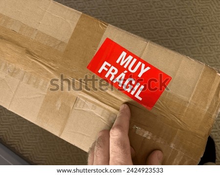 Male hand pointing to the Muy Fragil translated as very fragile from spanish language - cardboard box parcel delivery Foto stock © 