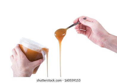 Male Hand Is Pouring Honey From Spoon Into The Jar Isolated On Background