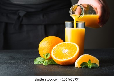 Male Hand Pouring Orange Juice Into A Glass.