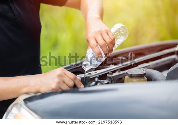 male
hand pouring water filling car radiator with concentrated coolant
or distilled water for cool engine in summer
season