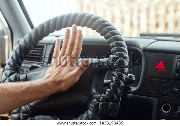Male hand presses\
the signal on the steering wheel of the car. Close-up. Emergency,\
accident, traffic\
violation.