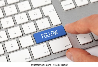 Male hand pressing blue button of computer keyboard.Concept of Follow.
