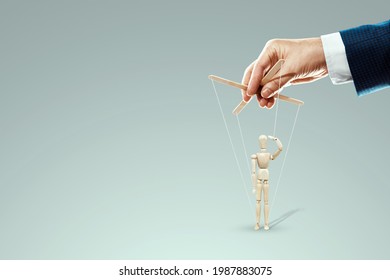 Male hand, puppeteer controls puppet, doll salutes, soldier. The concept of the army, orders, manipulation, control army