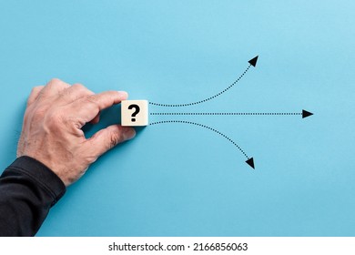 Male hand puts a wooden cube with question mark. Different solution alternatives for an emerging problem or alternative path options. - Shutterstock ID 2166856063