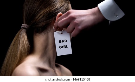 Male Hand Putting Bad Girl Label On Female Ear, Stereotypes About Women Behavior