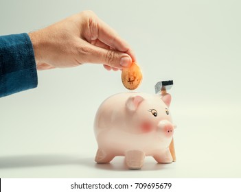 Male Hand Putting Bitcoin In To Piggy Bank. Cryptocurrency Investment Concept
