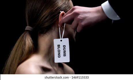 Male Hand Putting Dumb Blonde Label On Female Ear, Humiliation, Stereotypes