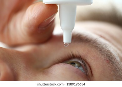 Male hand putting liquid drops in his eye solving vision problem closeup - Powered by Shutterstock