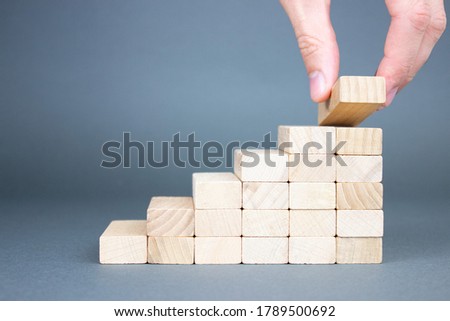 Male hand putting wooden blocks in the form of a ladder. The concept of building a success of the foundation.
