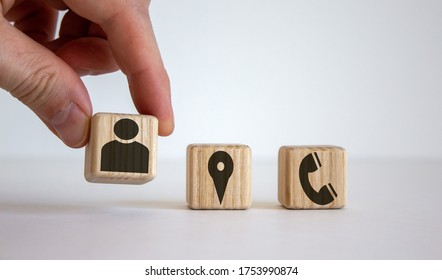 Male hand putting wooden cube with human icon near other cubes with geoposition and phone marks, contact and information icons.