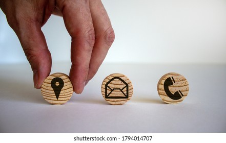 Male hand putting wooden cube with geoposition icon near other cubes with mail and phone marks, contact and information icons. Beautiful white background. Business concept. Copy space.