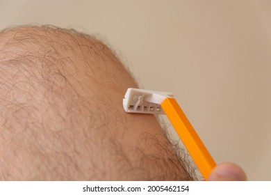 A Male Hand With Razor Shaving Hairy Legs At Home. Man Beauty Concept. Close Up, Selective Focus And Copy Space