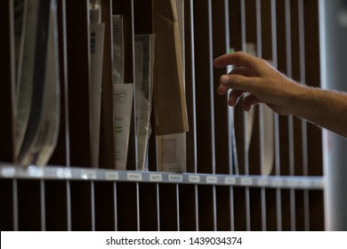 Male Hand Reaching For Sorted Post Or Mail In Pigeon Holes In A Postal Depot In A Corporate Business