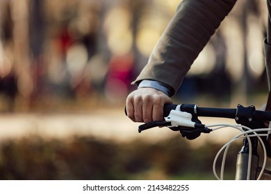Male hand riding a bike,  holding a handlebar.