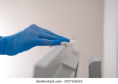 A Male Hand In Rubber Gloves Wipes The Dust From A Computer Monitor With A Napkin. Disinfection At Home, Cleaning In The Context Of The COVID-19 Pandemic.