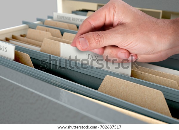 A male hand searching through documents in a filing\
cabinet drawer 