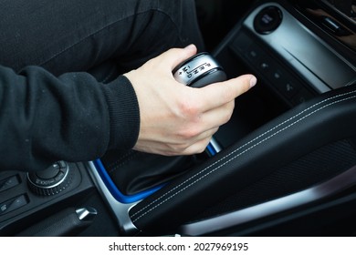 male hand shifts gears on the automatic transmission lever - Shutterstock ID 2027969195