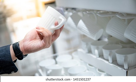 Male Hand Shopper Choosing With Ceramic Cup In Grocery Store. Buying Tableware Or Kitchenware. Home Decoration Concept