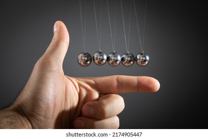 Male Hand Showing Newton's Cradle Balls.