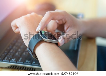 Male hand with smart watch on wrist, wearable watch and technology computer laptop for communication, checking time.