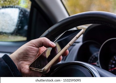 Male hand with smartphone on steering wheel of car - Shutterstock ID 1532595095