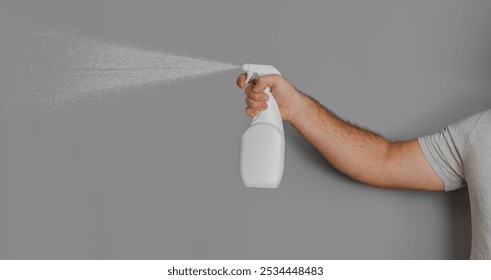 Male hand spray bottle with cleaning liquid. Studio photo, gray backdrop. Copy space for advertising - Powered by Shutterstock