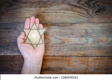 Male hand and star of David on a wooden board background. Holocaust Remembrance Day