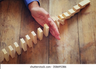 a male hand stoping the domino effect. retro style image executive and risk control concept