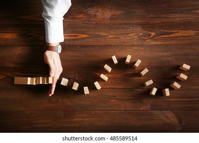 Männliche Hand, die den Dominoeffekt auf Holztisch stoppt