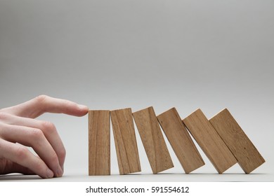 Male Hand Stopping Wooden Blocks Falling Over
