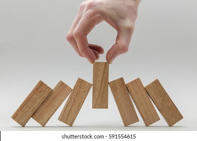 Male Hand Stopping Wooden Blocks Falling Over
