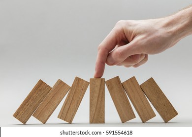 Male Hand Stopping Wooden Blocks Falling Over
