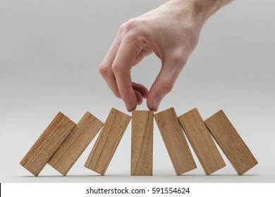 Male Hand Stopping Wooden Blocks Falling Over
