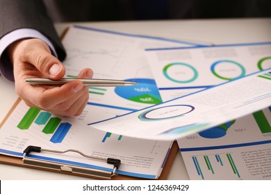 Male hand in suit hold siver pen in office with clipboard on table closeup. Comprehensive audit of enterprise business at all stages development. - Shutterstock ID 1246369429