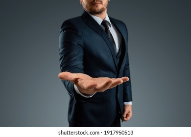 Male hand in a suit shows a palm up gesture on a gray background. Concept of request, bankruptcy, close-up - Powered by Shutterstock