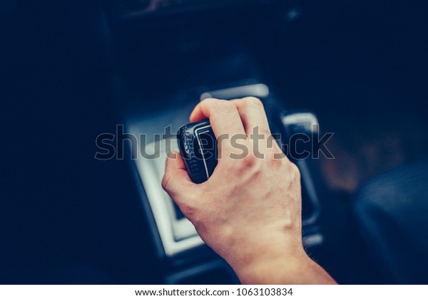 Male hand switches the automatic transmission
close-up. Close-up of the driver's arm includes mode Drive on the
gear lever automatic transmission of the luxury car. Stylish Toned
Photo Top view
