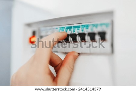 Male hand switching on fuse board.