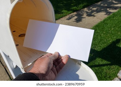 A male hand taking a blank white envelope out of a mailbox