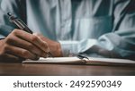 Male hand taking notes on the notepad. businessman working at work table, checklist writing planning investigate enthusiastic concept. focus on man hand holding pen, putting signature at official pape