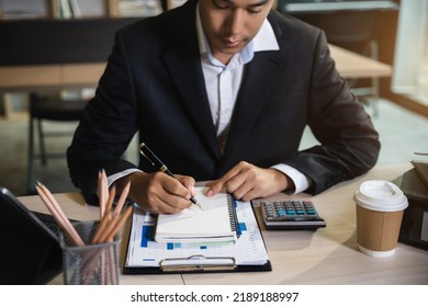 Male hand taking notes on a notebook handwritten note writing business schedule and use a laptop computer at the office desk in the morning. - Powered by Shutterstock