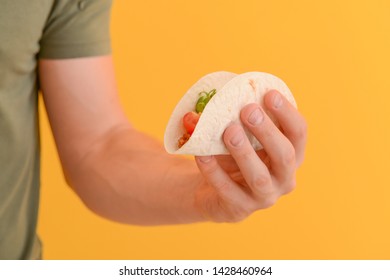 Male Hand With Tasty Taco On Color Background