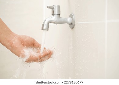 Male hand testing faucet strength from tap water in bathroom - Shutterstock ID 2278130679