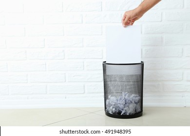 Male Hand Throwing Blank Sheet Of Paper Into Metal Trashcan