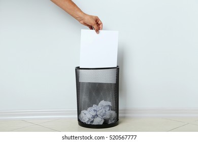 Male Hand Throwing Blank Sheet Of Paper Into Metal Trashcan