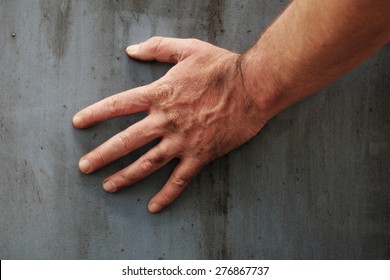 Male Hand Touching The Gray Grunge Surface Of A Stained Concrete Wall, Close-up