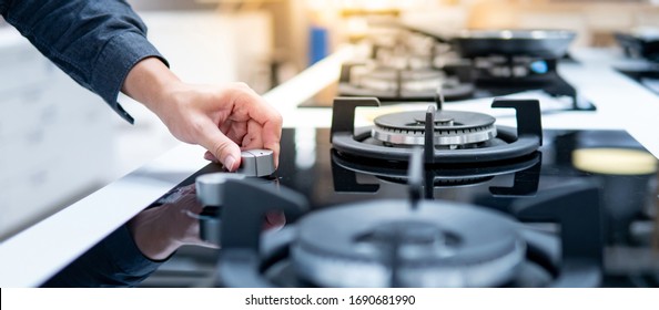 Male Hand Turning Switch Knob On Modern Gas Stove In Kitchen Showroom. Cooking Appliance In Domestic Kitchen. Home Improvement And House Interior Design Concepts