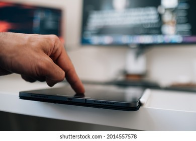 A male hand using his finger ID on a tablet at home or a public place to make an online purchase